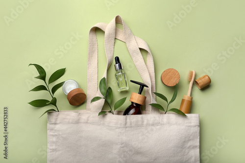 Foto Bag with eco friendly products on green background, flat lay