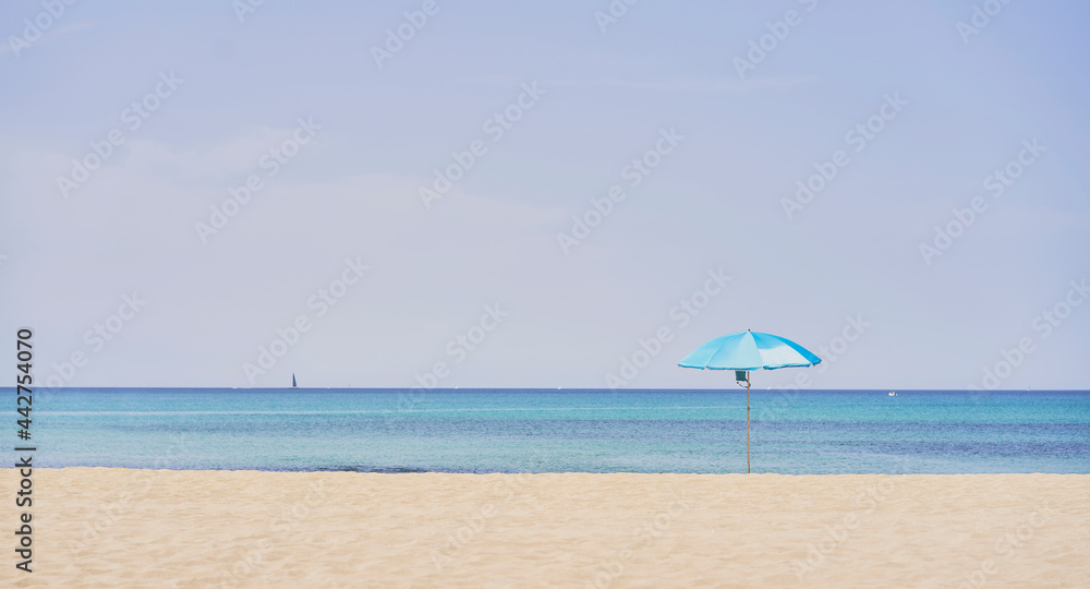 Summer concept. Blue umbrella, beach and blue sea on a beautiful sunny day
