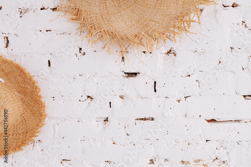 a straw hat on a background of a white brick wall with copy space. Travel concept