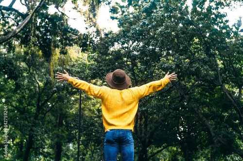 young man traveler raising arms on forest. outdoor therapy concept.