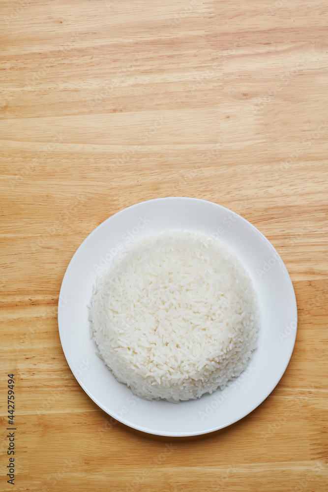 flat lay top view shot of streamed white Thai's jasmine rice in the white clean dish isolated put on the wooden plate dinner table closed to one conner of the photo with empty copy space for texts flat lay top view shot of streamed white Thai's jasmine rice in the white clean dish isolated put on the wooden plate dinner table closed to one conner of the photo with empty copy space for texts