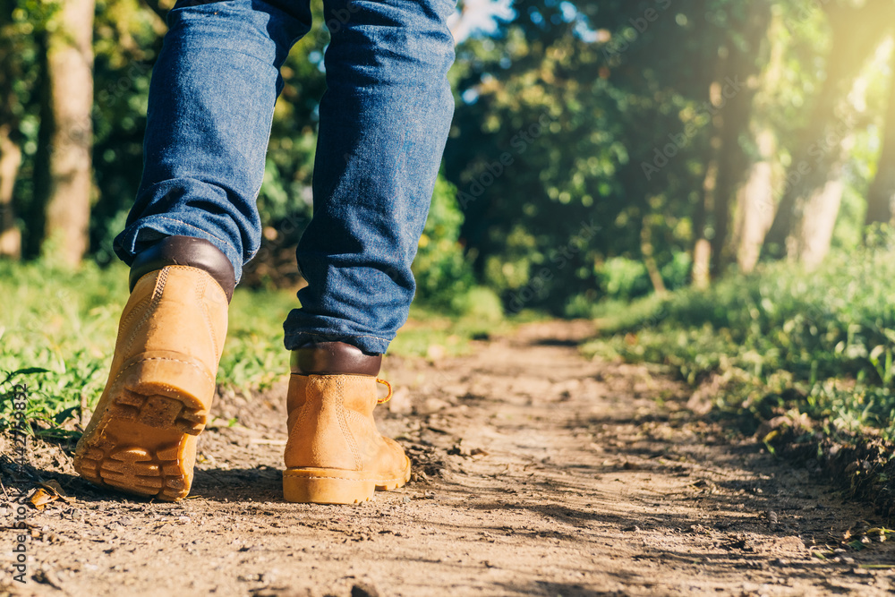 feets of an adult with boots to travel walking in a green forest. travel and hiking concept. feets of an adult with boots to travel walking in a green forest. travel and hiking concept.