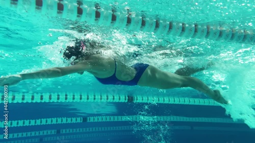 Underwater Shot: Fit Beautiful Swimmer doing Laps in Swimming Pool. Professional Female Athlete swims at Great Speed. Ready To Set World Championship Record. Colorful Artistic Stylish Tracking Shot photo