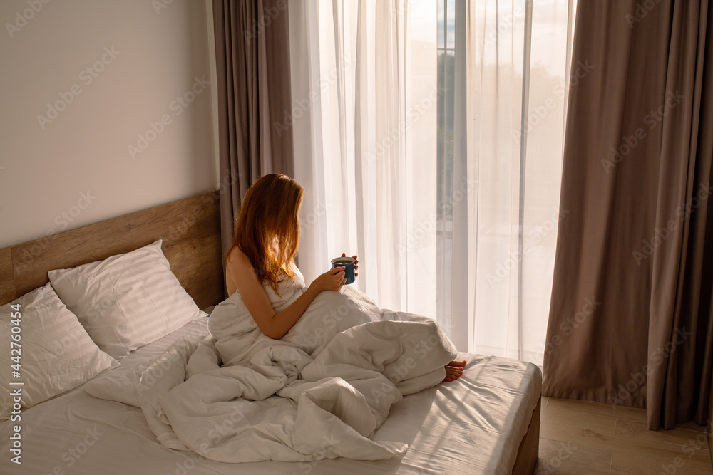 Girl in bed with coffee. Morning with coffee in bed. With coffee by the big window. Morning girls with coffee in bed. Bedroom. Sunrise in the bedroom. Awakening a girl in white bed linen with coffee. Girl in bed with coffee. Morning with coffee in bed. With coffee by the big window. Morning girls with coffee in bed. Bedroom. Sunrise in the bedroom. Awakening a girl in white bed linen with coffee.