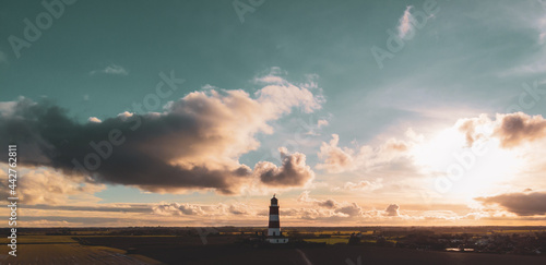 Lighthouse photo taken from the air in front of a cloudy sunset