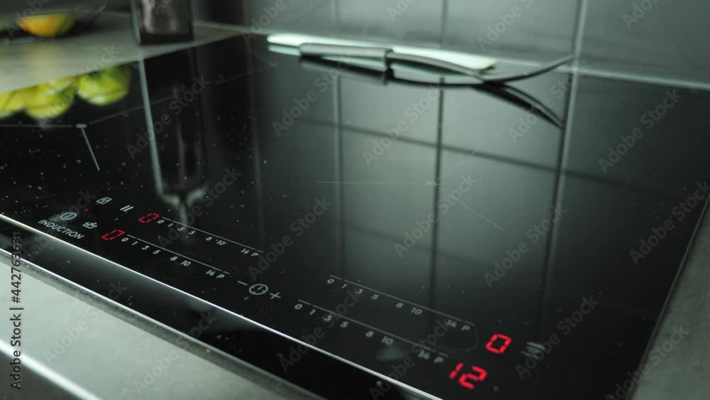 Hand turning on induction electric touch stove and putting pan on hob