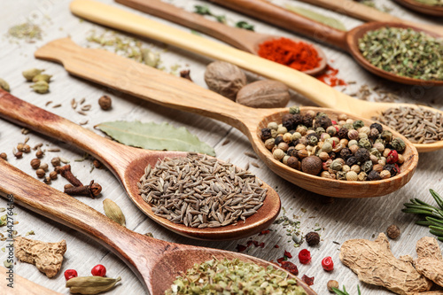 Different natural spices and herbs on light wooden table, closeup