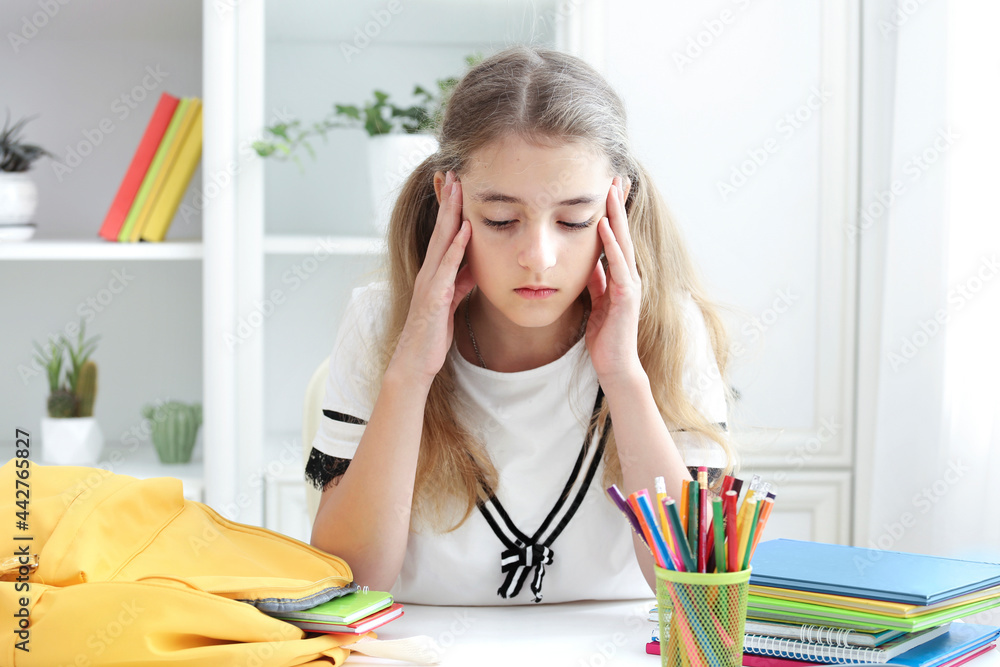 Child tired of education. School exams.Kid's headache. Uhappy girl sitting at desk. Pupil make homework. Caucasian schoolgirl in stress. Child tired of education. School exams.Kid's headache. Uhappy girl sitting at desk. Pupil make homework. Caucasian schoolgirl in stress.
