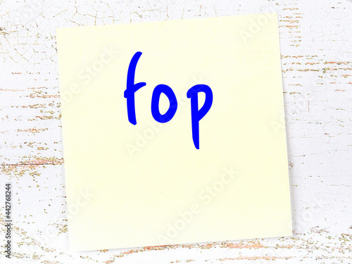 Foto Yellow sticky note on wooden wall with handwritten word fop