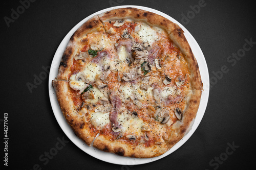 top view of italian pizza with ham  mushrooms and cheese on black background