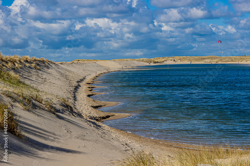 Camperduin lagoon with calm blue water surrounded by dunes with brown sand and marram grass, sunny day with a blue sky and white clouds in North Holland in the Netherlands photo