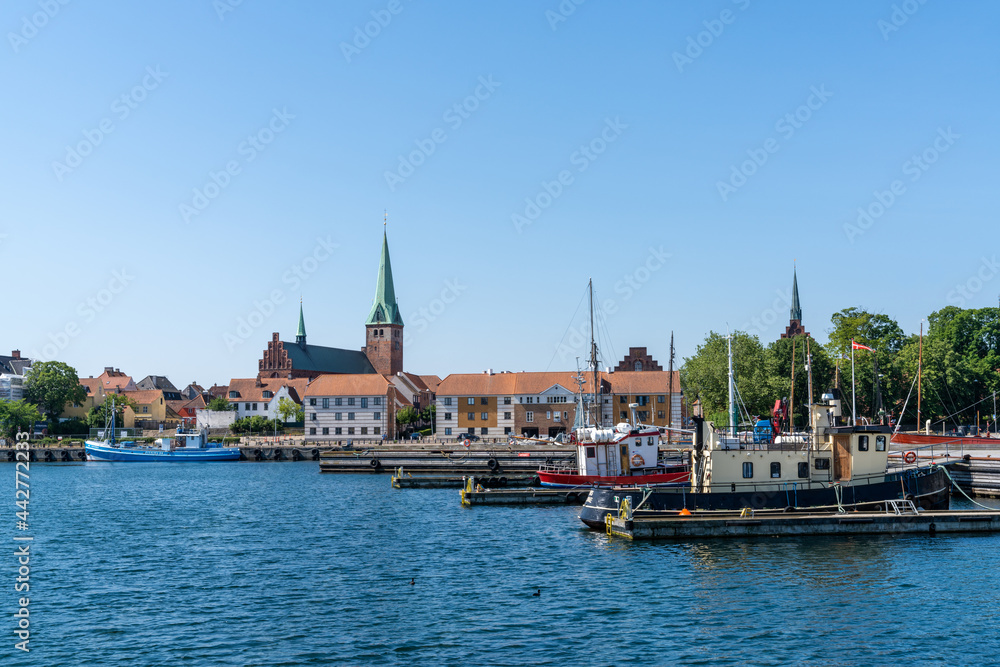 cityscape of the harbor and old town of Helsingor in northern Denmark with colorful fishing boats in the foreground
