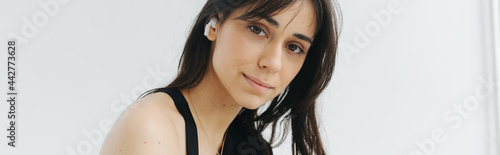 brunette armenian woman in earphone looking at camera on white, banner photo