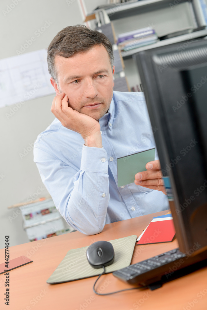 Fototapeta premium Man reading card and computer screen