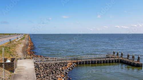 Small jetty between stones with part of the causeway at Afsluitdijk with the lake IJssel created by closing part of the Zuiderzee in the background, sunny day on IJsselmeer in the Netherlands photo