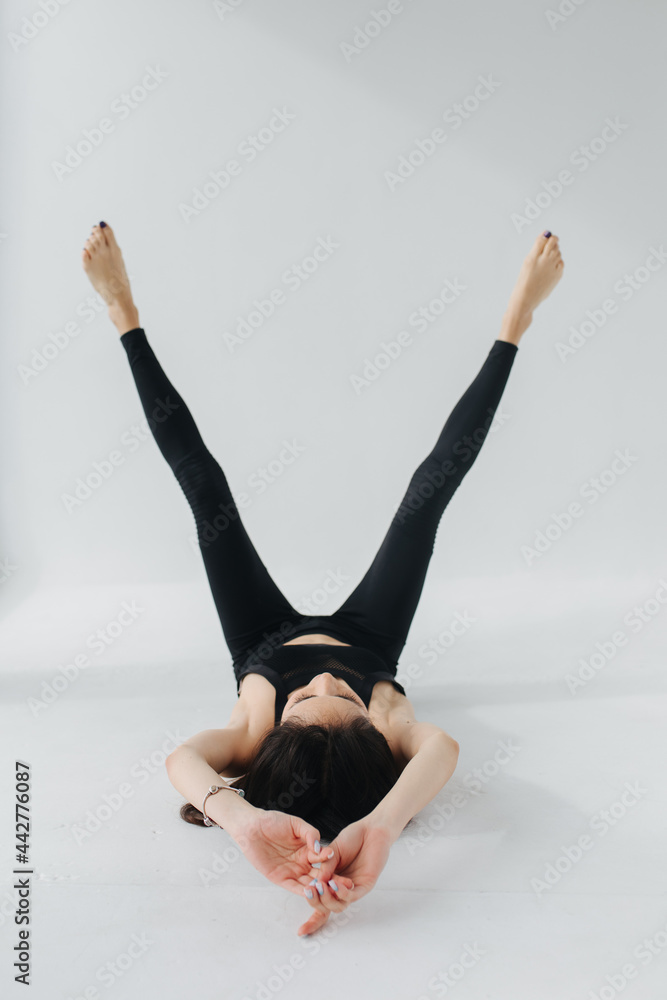 barefoot armenian woman in black leggings practicing yoga in rejuvenation pose on white