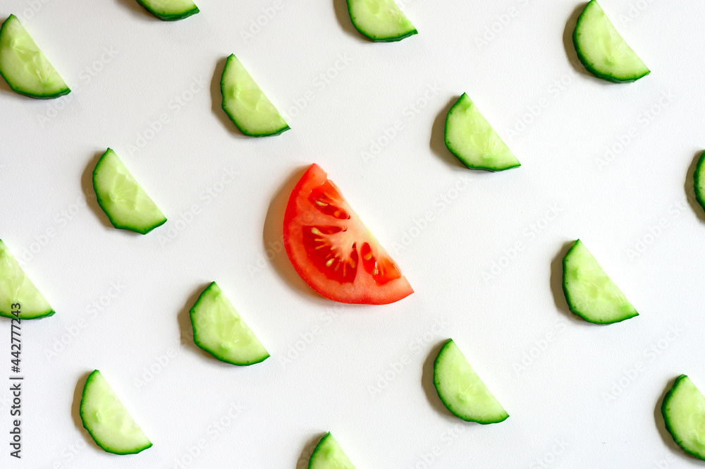repeating pattern of sliced semicircles of fresh raw vegetable cucumbers for salad and a slice of tomato in the center isolated on a white background flat lay, top view repeating pattern of sliced semicircles of fresh raw vegetable cucumbers for salad and a slice of tomato in the center isolated on a white background flat lay, top view
