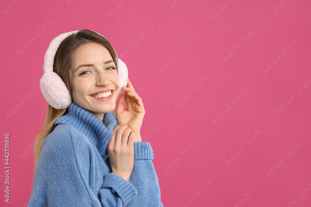 Happy woman wearing warm earmuffs on pink background, space for text Happy woman wearing warm earmuffs on pink background, space for text