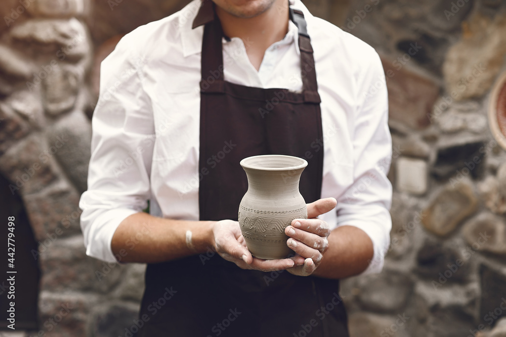 Man in a brown apron standing wit a vase Man in a brown apron standing wit a vase