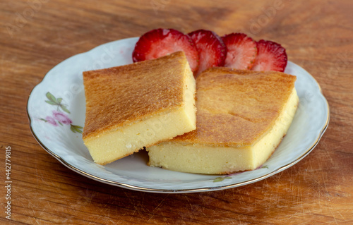 Two pieces of fiadone - Corsican cheesecake, on a saucer with strawberry slices. photo