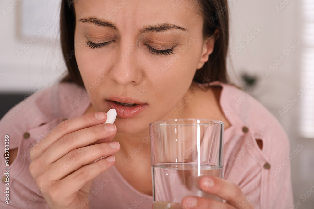 Sad young woman taking abortion pill at home, closeup Sad young woman taking abortion pill at home, closeup