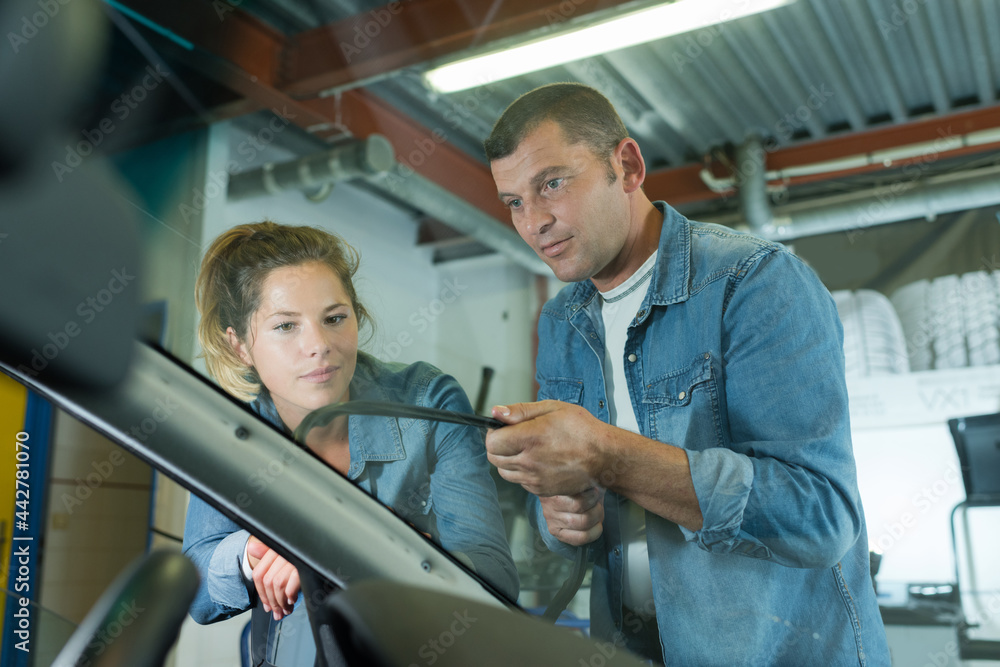 man and woman workier during car windshield replacement man and woman workier during car windshield replacement