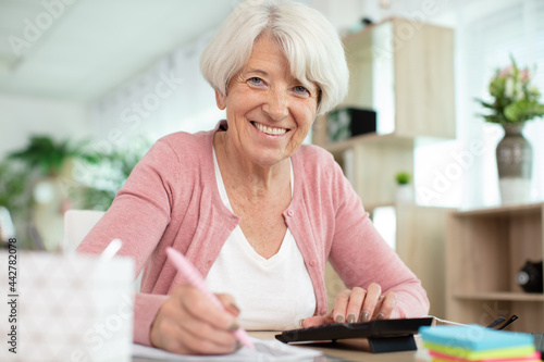 senior woman with calculator and bills counting money at home