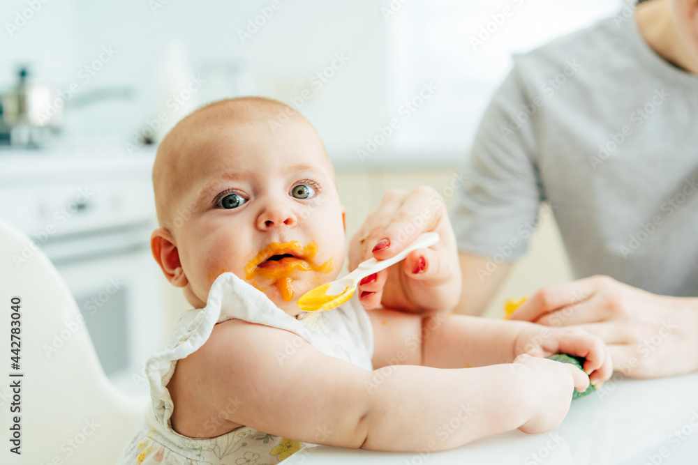 Close-up of an infant's face stained with vegetable puree. Mom feeds the baby. Close-up of an infant's face stained with vegetable puree. Mom feeds the baby.