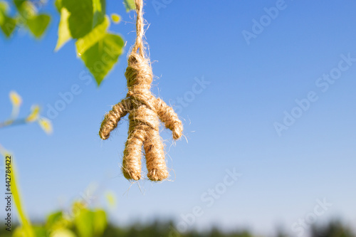 Homemade amulet doll made of twine hanging against blue sky background. Traditional folk doll for defender home. photo