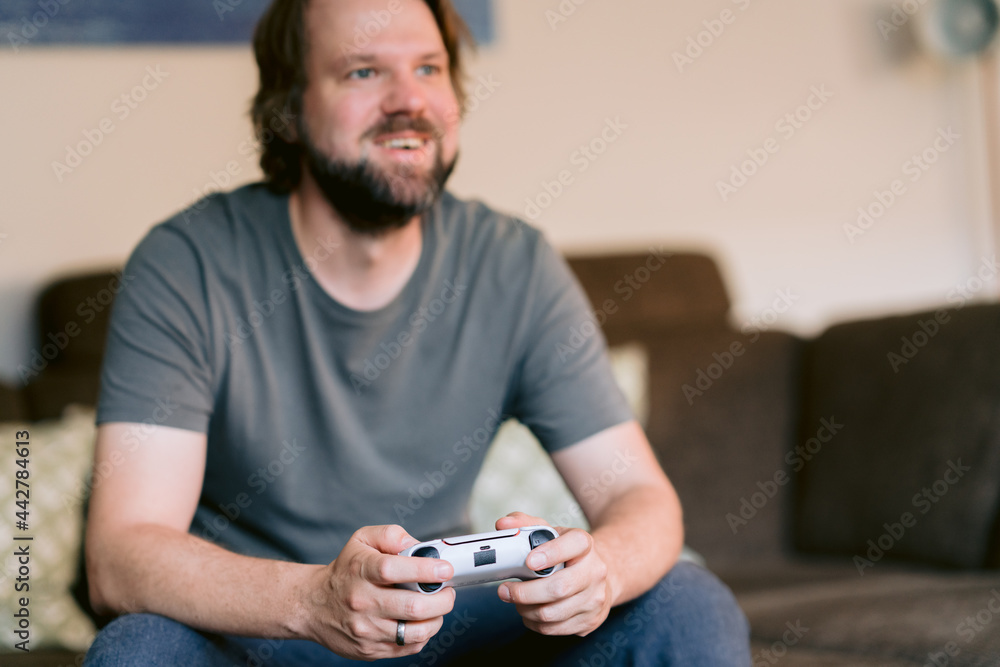 Mann hält einen Controller in den Händen, lächelt und spielt ein Computerspiel Mann hält einen Controller in den Händen, lächelt und spielt ein Computerspiel