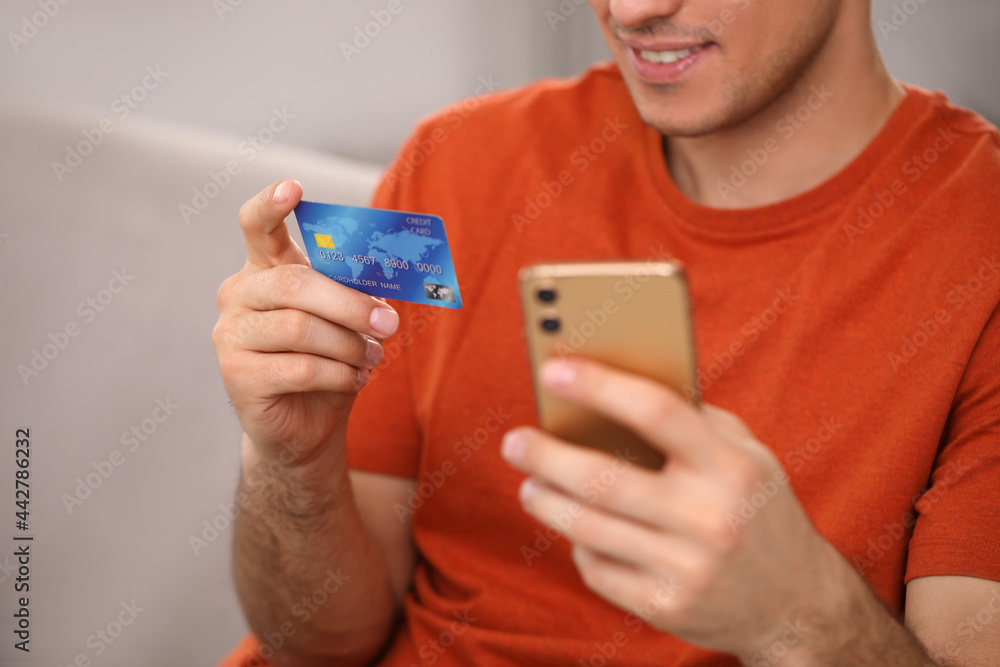 Man using smartphone and credit card for online payment at home, closeup Man using smartphone and credit card for online payment at home, closeup