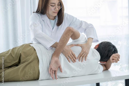 Female doctor doing physical therapy By extending the back of a male patient