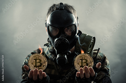 man in gas mask holding bitcoin coins in hands