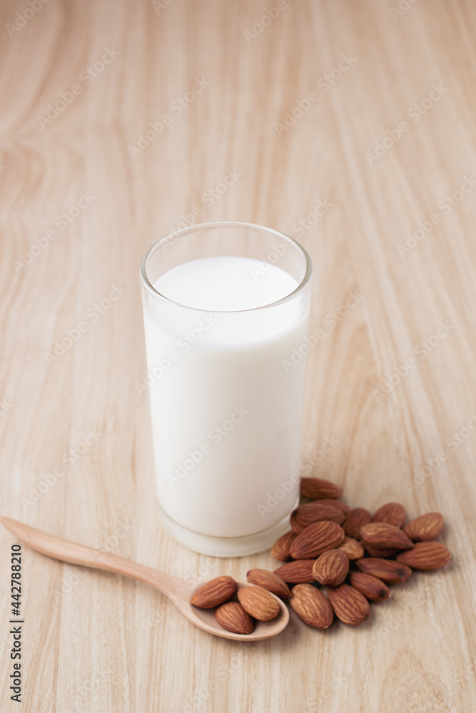 almond milk in glass on wood background with nuts around the bowl.selective focus.front view.copy space. almond milk in glass on wood background with nuts around the bowl.selective focus.front view.copy space.