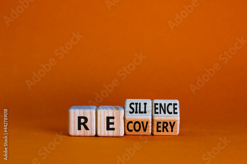 Recovery and resilience symbol. Turned wooden cubes and changed the word 'recovery' to 'resilience'. Beautiful orange background. Business and recovery - resilience concept. Copy space.