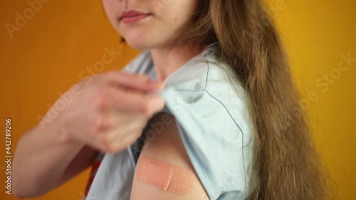 People get vaccinated, female teenager receive covid-19 vaccine, smile face, pink bandage on arm, yellow background studio footage, 