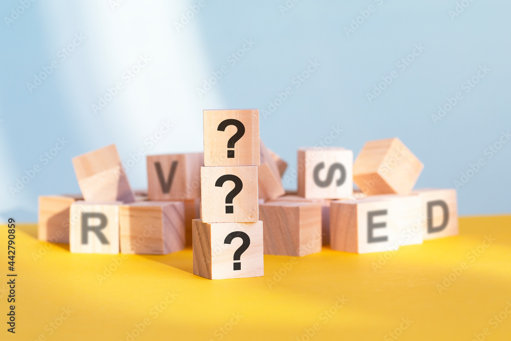 three question marks written on wooden cubes, yellow background three question marks written on wooden cubes, yellow background