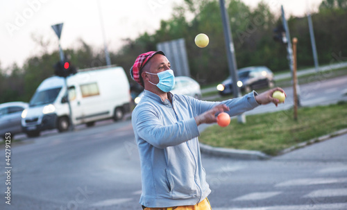 A juggler working in traffic. Juggler man performing at the traffic lights, after the presentation he asks the drivers for a donation.