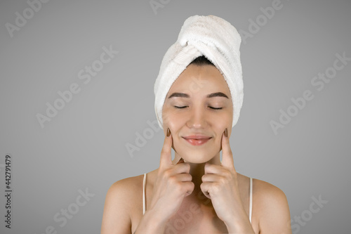 Washing your face. Closeup of woman cleaning skin with towel portrait. The woman touches her skin with her hands and smiles. High quality studio shot. 