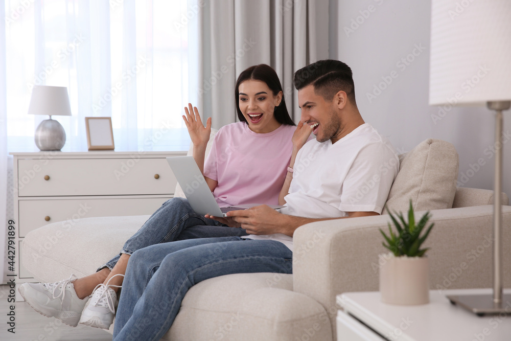 Emotional couple participating in online auction using laptop at home