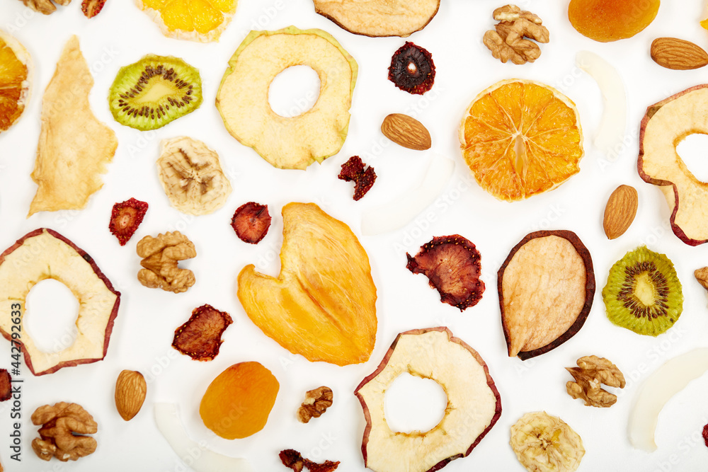 Close up of dried strawberry,almonds, dried apricot, raisins, walnuts, dried apples and kiwi on white background. Concept of organic healthy assorted dried fruit for snacks.