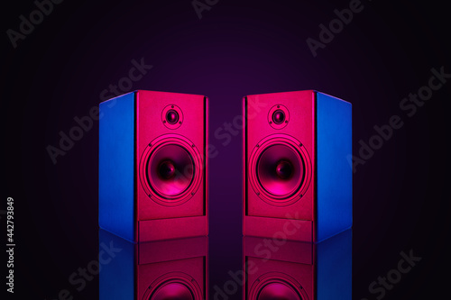 Two neon colored stereo speakers on dark background with reflection.Sound audio loud speakers, close up