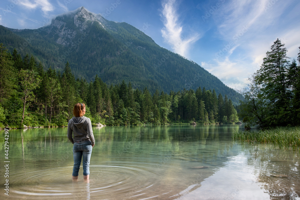 Young woman standing at shore of crystal clear mountain lake in Germany