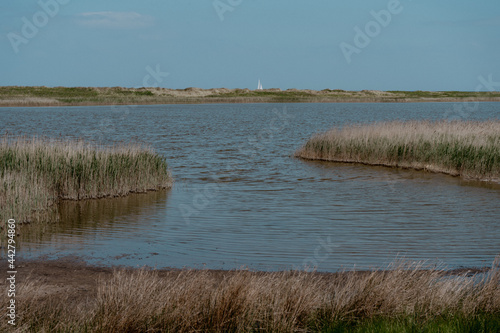 Kleiner See an der K  ste mit Seegelboot am Horizont