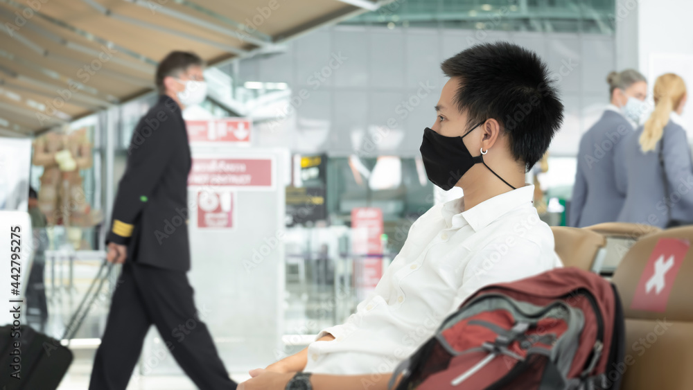 Man with luggage in airport terminal. Social distancing, International airport, on holiday, Corona virus, passenger wearing protective mask, after Covid-19, outbreak, Finding solitude Man with luggage in airport terminal. Social distancing, International airport, on holiday, Corona virus, passenger wearing protective mask, after Covid-19, outbreak, Finding solitude
