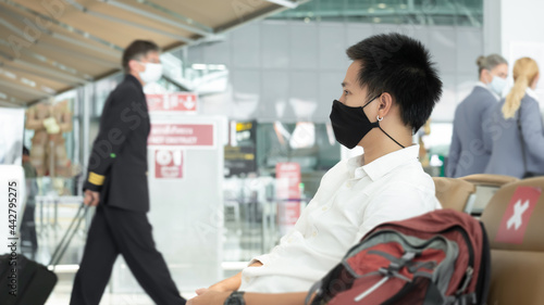 Man with luggage in airport terminal. Social distancing, International airport, on holiday, Corona virus, passenger wearing protective mask, after Covid-19, outbreak, Finding solitude 