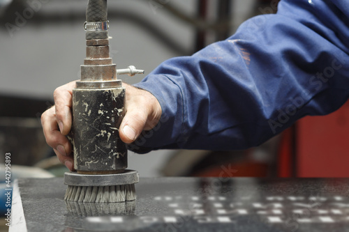 Obraz na płótnie Hand of a worker processing a granite monument with a dustless sandblaster