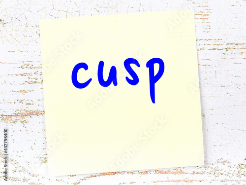 Фотография Yellow sticky note on wooden wall with handwritten word cusp