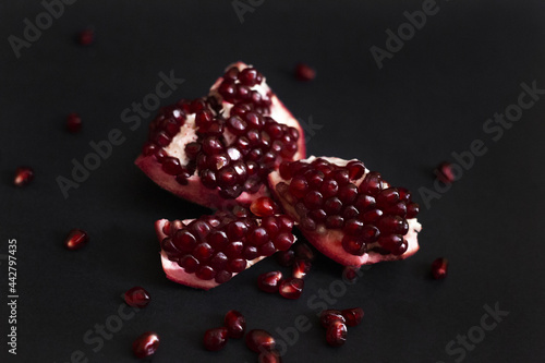 Crop of opened pomegranate and seeds on the dark background photo