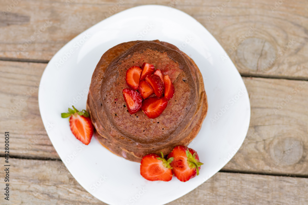 chocolate pancakes with strawberries on a white plate. chocolate pancakes with strawberries on a white plate.